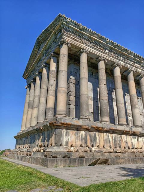 Classical columns of the pagan Temple of Garni against a bright blue sky