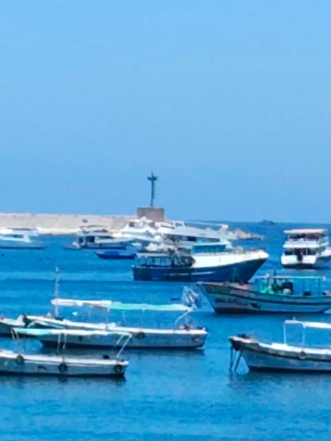 Soft-focus image of pleasure boats moored on vivid blue water near a low sea wall
