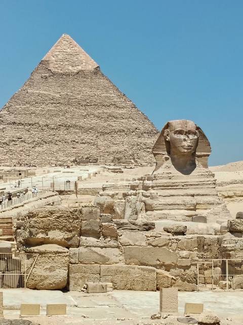 Classic profile of the Great Sphinx with the Great Pyramid towering behind under blue sky