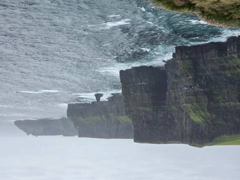 Dramatic view of the Cliffs of Moher plunging into a choppy Atlantic under grey skies