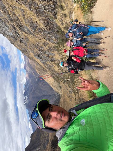 High-altitude trail with trekkers posing against vast Andean valleys and peaks