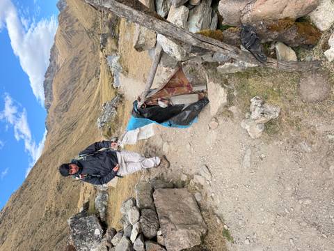 Trekker walking along a stony mountain path with simple stone walls