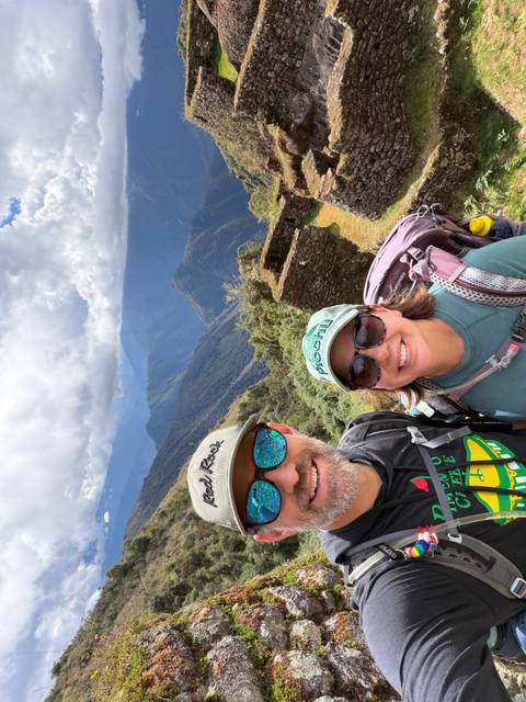 Couple taking a selfie above verdant valleys and Inca ruins in the Andes