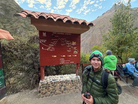 Young hiker standing beside an information signboard that maps the Inca trail route