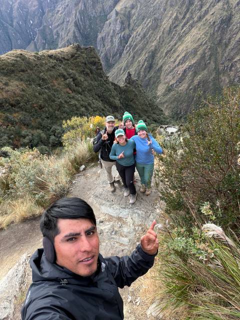 Family of trekkers posing on a rocky viewpoint above a lush ravine