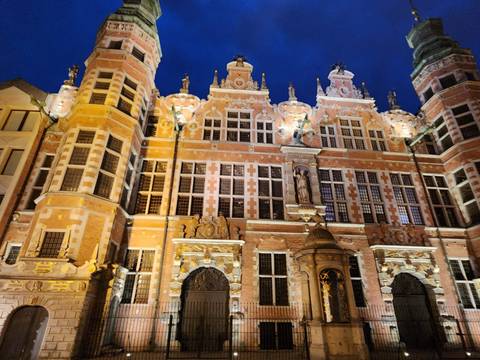 Illuminated ornate Renaissance-style façade of a historic building glows against a deep night sky.