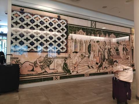 Large decorative wall mural of historic figures and patterns inside a modern building lobby.