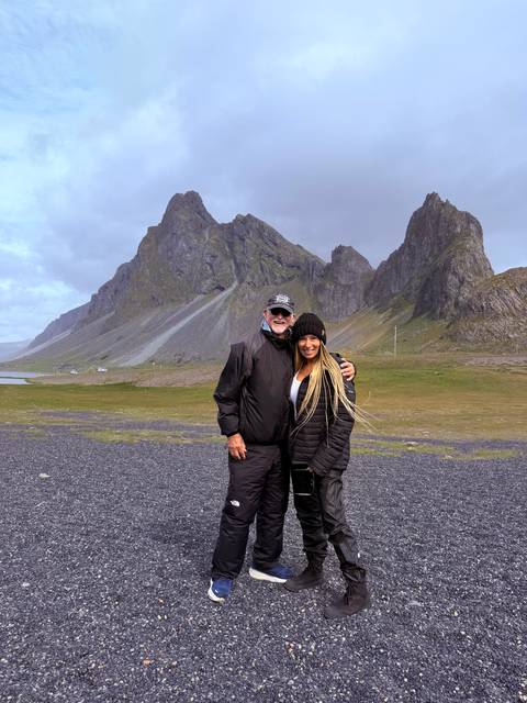 Couple posing in front of dramatic jagged mountains and a pebbled plain