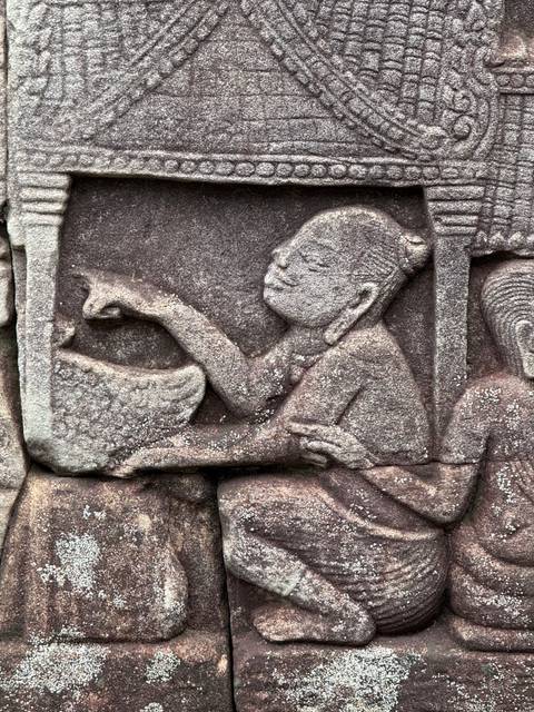 Detailed close-up of an ancient sandstone bas-relief carving of a seated figure