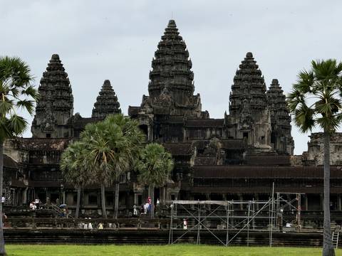 Closer view of Angkor Wat towers framed by palm trees under grey skies