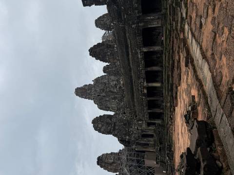 Dark, moody view of Bayon-style temple towers under a grey sky