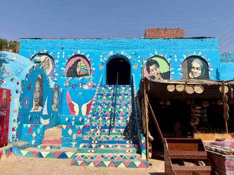 A vividly painted Nubian house adorned with murals and geometric stairs.
