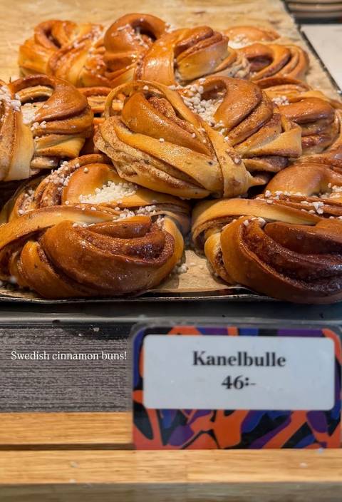 Close-up of freshly baked Scandinavian cinnamon buns sprinkled with pearl sugar in a bakery tray.