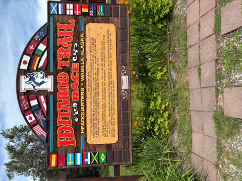 Colorful Iditarod Trail Race headquarters sign decorated with international flags in Wasilla, Alaska.