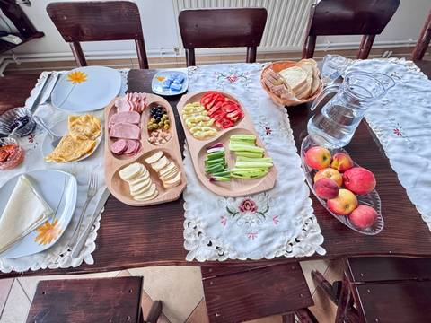 Breakfast spread of cold cuts, cheese, vegetables and fruit beautifully arranged on a lace-draped table.