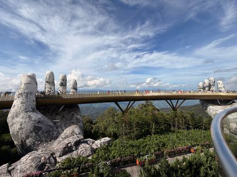 Iconic Golden Bridge supported by giant stone hands spans high above Ba Na Hills near Da Nang.