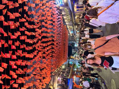 Crowded night market street festooned with rows of red Vietnamese flags and lively bars in Ho Chi Minh City.