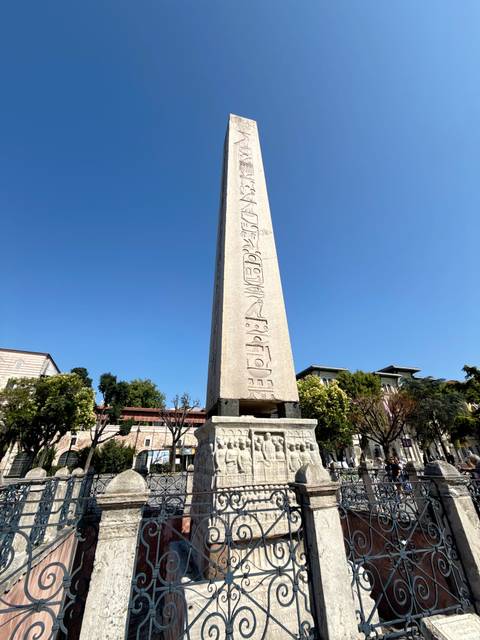 Ancient stone obelisk with hieroglyphs standing against clear blue Istanbul sky