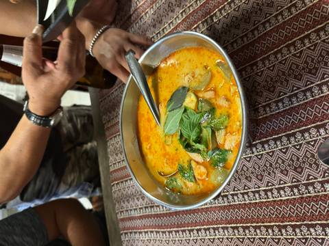 Bowl of spicy creamy soup garnished with basil leaves on a patterned tablecloth