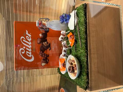 Window display featuring Swiss Cailler chocolate box with pralines, milk bottle and decorative cows