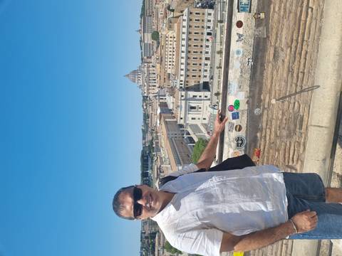 Smiling traveler on a sunny terrace overlooking St. Peter's Basilica and the rooftops of Rome.
