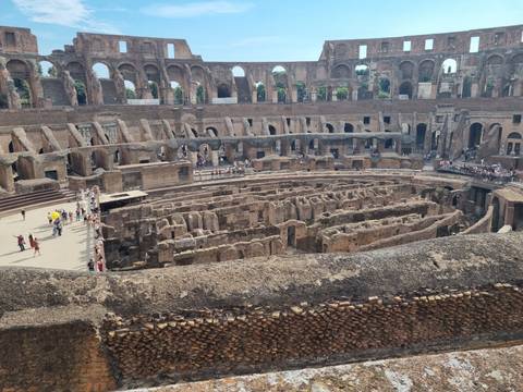 Interior arena view of the Colosseum revealing excavated corridors crowded with tourists.
