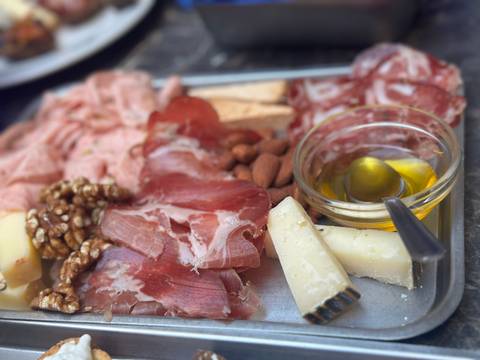 Board of cured meats, cheese, nuts and olive oil presented for tasting.