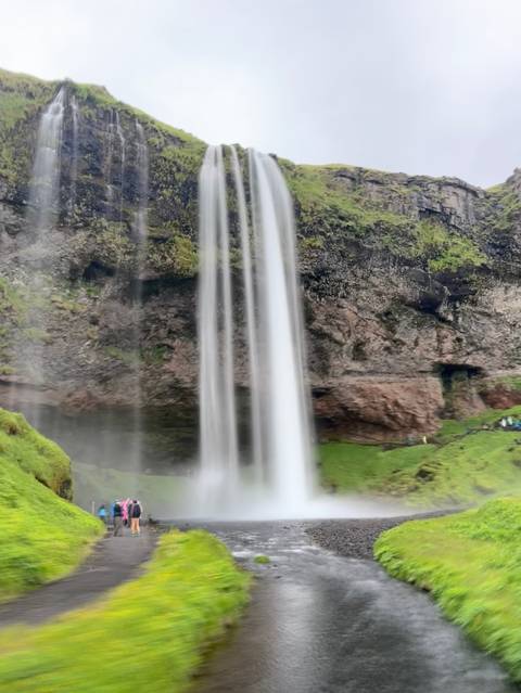 Blurred close-up of a tall waterfall plunging over a mossy cliff.