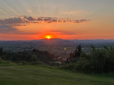 Vibrant sunset over a wide Greek valley with mountains silhouetted against an orange sky