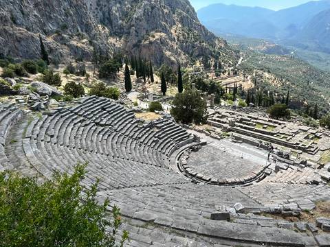 Ancient stone theatre of Delphi overlooking a lush valley and distant hills