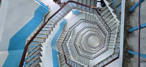 View looking down a blue-and-white spiral staircase with safety netting in the center
