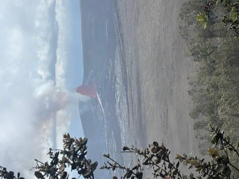 Active volcano erupting with red lava fountain and plume of smoke viewed from distance