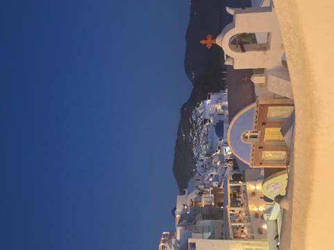 Evening view of whitewashed Santorini village and domes under deep blue twilight.