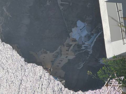Zoomed view of cliffside cave dwellings and structures along Santorini caldera wall.