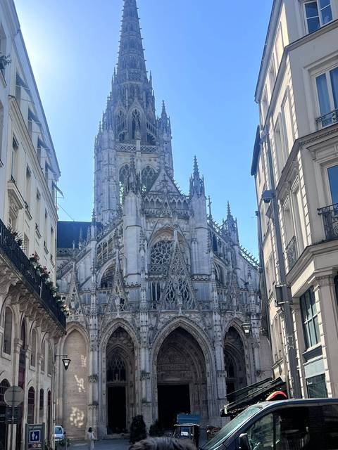 Imposing Gothic Rouen Cathedral rising between narrow city streets under clear sky