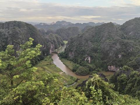 A winding river cuts through lush karst mountains under a pastel evening sky.