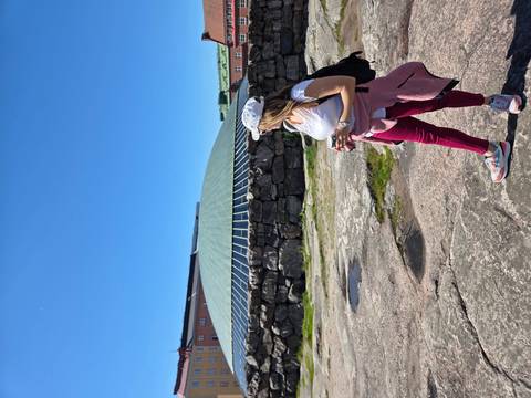 Traveler looks toward the green domed rock-hewn Temppeliaukio Church set against a clear blue sky.
