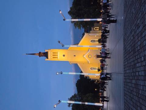 Tallinn's yellow St. John's Church is illuminated at dusk as crowds gather in the square.