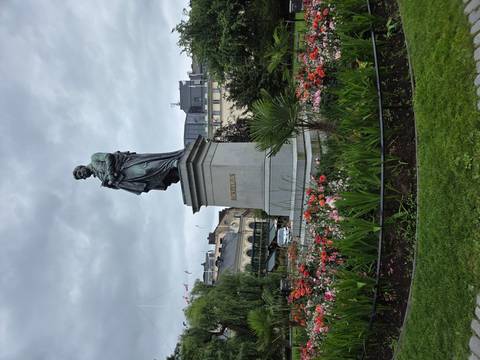Statue of chemist Berzelius stands amid colourful flower beds in a city park.