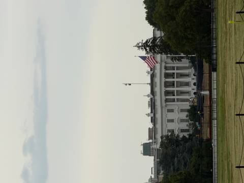 Distant view of the White House with American flag flying at half-mast on a calm day.