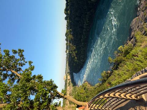 Turquoise river winding through a green wooded gorge under a clear morning sky.