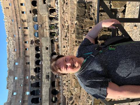 Woman inside the Colosseum interior smiling beside ancient stone tiers.