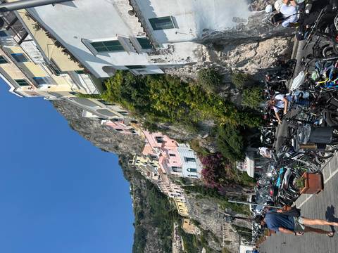 Colorful cliffside houses of Amalfi coast rising above a busy street filled with bikes and scooters.