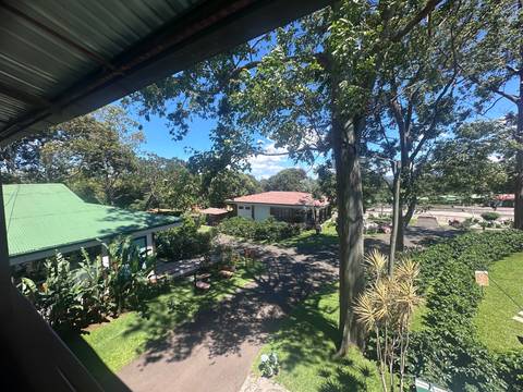 Resort grounds seen from an elevated balcony with gardens and cottages under blue sky.