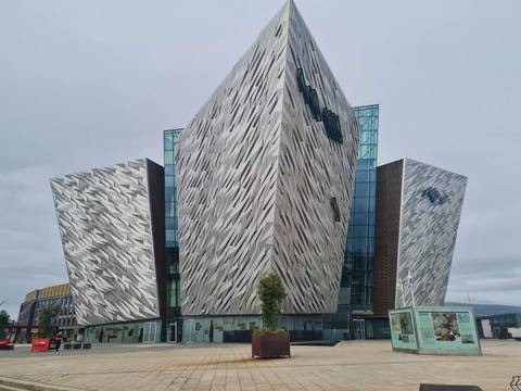 Modern angular façade of the Titanic Belfast museum clad in patterned aluminum panels against grey skies.