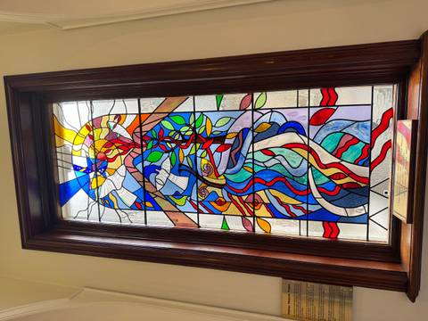 Vibrant stained glass window featuring abstract colorful design framed in dark wood.