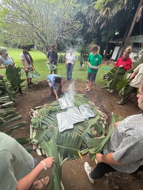 Participants prepare a traditional underground imu oven covered with banana leaves.