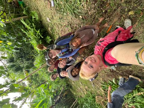Energetic selfie of travellers in lush jungle holding a fresh coconut.