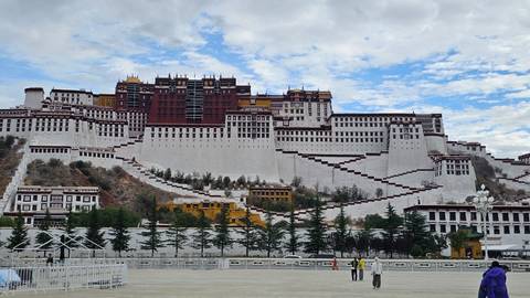 Detailed frontal view of the white-red Potala Palace rising against a patchy blue sky.