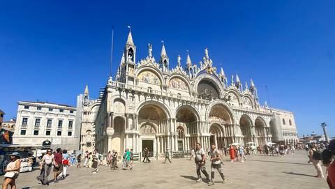 St. Mark's Basilica dominates Venice's Piazza San Marco under a vivid blue sky with crowds below.